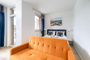 an orange couch in a room with a bed at Your Holidays Bel Mare Aqua in Międzyzdroje