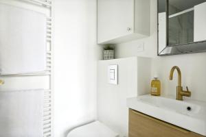 ein weißes Bad mit einem Waschbecken und einer Dusche in der Unterkunft PL1 - Stylish architect studio near Le Marais in Paris