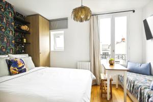 Schlafzimmer mit einem Bett, einem Tisch und einem Fenster in der Unterkunft PL1 - Stylish architect studio near Le Marais in Paris