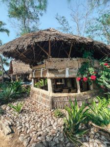 a building with a straw hut with flowers at Che Shale in Mambrui