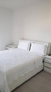 uma cama branca com lençóis e almofadas brancos em Paradise Dream 3 Apartment in Vlora em Vlorë