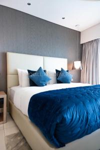 a bedroom with a large bed with blue sheets and pillows at Quill Residence at Paramount Towers 3 BR Creek View in Dubai