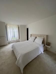 - une chambre blanche dotée d'un grand lit avec des draps et des oreillers blancs dans l'établissement Charming Barbizon Villa, à Barbizon