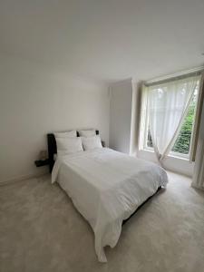 - une chambre blanche avec un grand lit et une fenêtre dans l'établissement Charming Barbizon Villa, à Barbizon