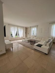 a large living room with white furniture and a tv at Charming Barbizon Villa in Barbizon