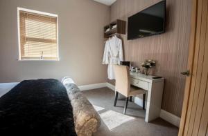 a bedroom with a bed and a desk and a television at The George Wright Boutique Hotel, Bar & Restaurant in Rotherham