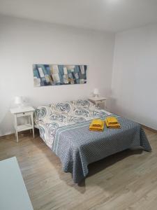 a bedroom with a bed with two yellow towels on it at Piso Avenida junto a la Playa in Cádiz