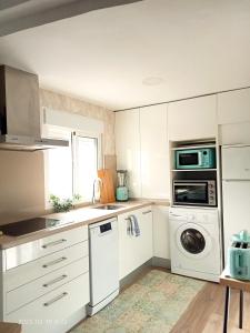 cocina con armarios blancos, lavadora y secadora en Luminosa habitación, en Sevilla