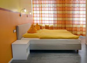 a bed with yellow sheets and pillows in front of a window at Hotel am Bahnhof in Aachen