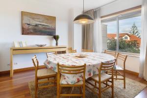 een eetkamer met een tafel en stoelen en een raam bij Villa Luzya in Viana do Castelo