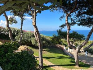 einen Garten mit Bäumen und dem Meer im Hintergrund in der Unterkunft GranAlacantHoliday mit traumhaften Meerblick und grossem Pool in Gran Alacant