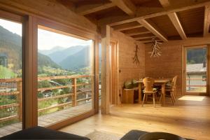 een kamer met een tafel en een balkon met uitzicht bij DESIGN-CHALETS by Pferd auf Wolke NEU in Gaschurn