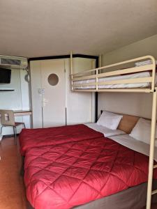 a bedroom with two bunk beds with red sheets at Première Classe Chateauroux - Saint Maur in Saint-Maur