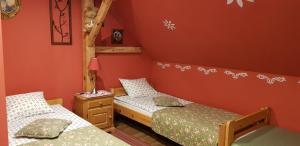 two twin beds in a room with red walls at Pod Lasem 