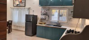 uma cozinha com armários azuis e um frigorífico preto em The Candy Studio em Ranchi
