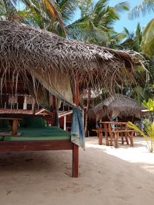 a straw hut on the beach with tables and chairs at Ibisbird Beach Bungalow in Tangalle