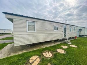 uma pequena casa branca com um jardim de relva em 6 Berth Caravan With Wifi At Steeple Bay Holiday Park In Essex Ref 36092f em Southminster