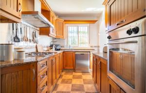 eine Küche mit Holzschränken und Geräten aus Edelstahl in der Unterkunft Gorgeous Home In Chiclana De La Fronter in Chiclana de la Frontera