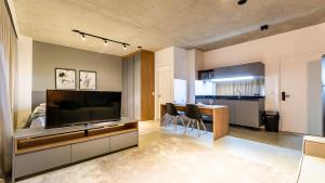 a living room with a large television and a kitchen at Studio luxuoso com vaga no Itaim Bibi - VN 1307 in São Paulo