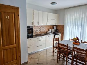 una cucina con armadi bianchi e tavolo con sedie di Apartment Hrastov a Soline