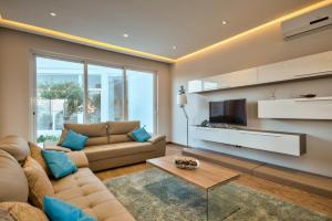 a living room with a couch and a tv at Villa Ghea - Indoor Jacuzzi Pool, Sauna and Games Room in Mellieħa