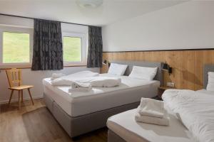 1 Schlafzimmer mit 2 Betten, einem Stuhl und 2 Fenstern in der Unterkunft Alpenhaus Montafon in Gargellen