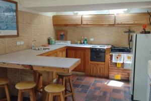 een keuken met houten kasten en een aanrecht met krukken bij Casa Tomine in Guatavita +16 foto's