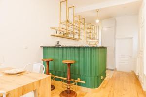 a kitchen with a green wall and wooden tables and stools at Cosy Loft between Montparnasse & Luxembourg Gardens in Paris