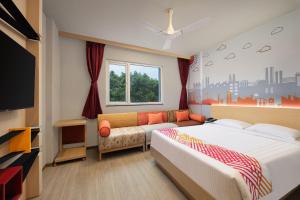 a bedroom with a bed and a couch and a tv at Ginger Noida 63 in Noida