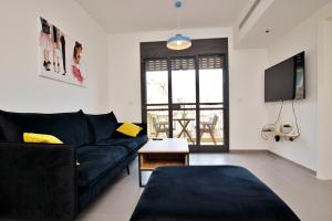a living room with a black couch and a tv at beautiful 2 bedrooms apartment with balcony in Tel Aviv