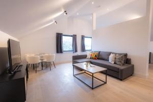 a living room with a couch and a table at Stylish Apartments with Balcony for upper apartments & Free Parking in a prime location - Five Miles from Heathrow Airport in Uxbridge