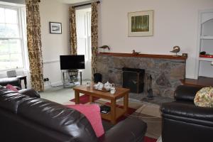 a living room with a couch and a fireplace at Craignuisq Farmhouse in Pitlochry