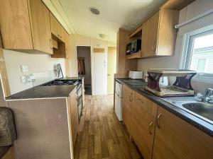 a kitchen with wooden cabinets and a counter top at Superb Caravan With Free Wifi At Seawick Holiday Park Ref 27022s in Clacton-on-Sea