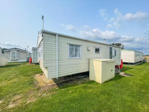 a mobile home in a yard next to a house at Superb Caravan With Free Wifi At Seawick Holiday Park Ref 27022s in Clacton-on-Sea