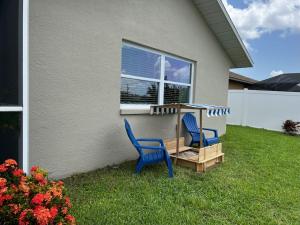 two blue chairs sitting in the grass in front of a house at Heated pool, Family Fun, Tiki Bar, kayak, 3bd 2ba in Cape Coral