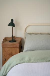 1 dormitorio con cama y mesita de noche con lámpara en The Roost, en Westport