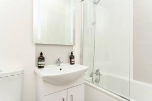 a white bathroom with a sink and a shower at The Penthouse In Bonchurch Village by Greenstay Serviced Accommodation - Stunning 3 Bed Apt With Parking & Sea Views - The Perfect Choice For Families, Small Groups & Business Travellers in Ventnor