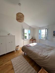 - une chambre blanche avec un grand lit et 2 fenêtres dans l'établissement Grande maison proche de la plage, à La Couarde-sur-Mer