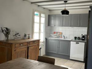 - une cuisine avec des placards gris, un évier et une table dans l'établissement Grande maison proche de la plage, à La Couarde-sur-Mer