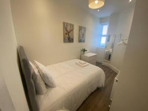 a white bedroom with a bed and a bathroom at Space Apartments - Two Bed Seafront Apartment with Off Street Parking - Windfarmer Accommodation - Flat 1 in Harwich