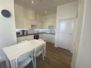 a white kitchen with a white table and chairs at Space Apartments - Two Bed Seafront Apartment with Off Street Parking - Windfarmer Accommodation - Flat 1 in Harwich