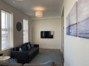 a living room with a couch and a tv at Space Apartments - Two Bed Seafront Apartment with Off Street Parking - Windfarmer Accommodation - Flat 1 in Harwich