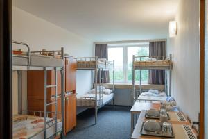 Schlafsaal mit 3 Etagenbetten und einem Tisch in der Unterkunft TVM Tower Modřany in Prag
