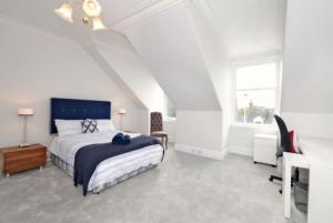 a white bedroom with a bed and a desk at Luxury West End Apartment in Aberdeen