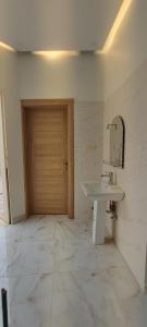 a bathroom with a sink and a wooden door at شقة ثلاث غرف نوم بريدة حي الحمر in Buraydah