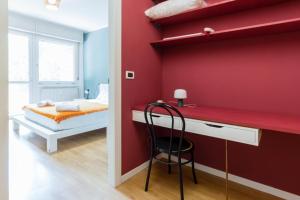 ベルガモにあるCasa Del Cactus - Bergamo City - by Host4Uの赤い壁の客室で、デスク、ベッドが備わります。