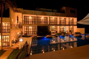 a building with a swimming pool at night at Milie Lounge Pousada in Japaratinga