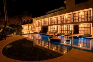 a large building with a swimming pool at night at Milie Lounge Pousada in Japaratinga