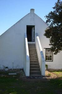 a white building with stairs leading to a door at De Mond Farm Cottage - Vogelgezang Farm (near Arniston) in Bredasdorp