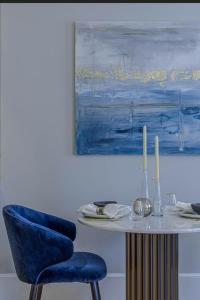 a table with a blue chair next to a painting at Uber Mayfair Luxury Apartment in London